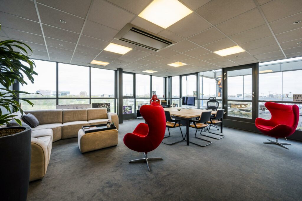 Modern ingericht kantoor aan de Anthony Fokkerweg met grote ramen, comfortabele zitplekken en een vergadertafel.